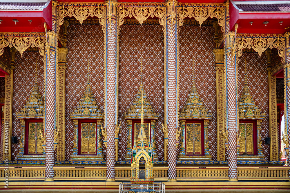 Obraz premium Intricate wall pattern and ornate window details of a Thai temple.