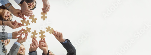 Slika na platnu White copy space banner or header background with a team of happy young business people playing with a wooden jigsaw puzzle