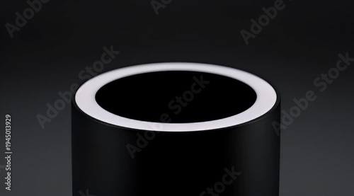 Sleek black cylindrical object with illuminated white ring on top against dark background