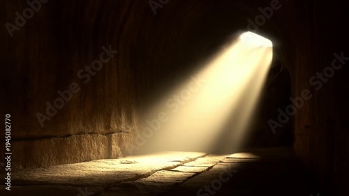 A shot from inside a dark cave tomb with a beam of morning sunlight illuminating the entrance concept of the empty tomb and resurrection
