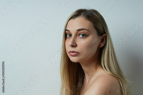 Natural portrait of a young woman with long hair in profile against a neutral background. Minimalist studio photo highlighting natural beauty, healthy skin, and authentic expression. 