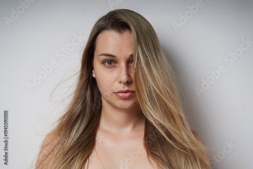 Natural portrait of a young woman with long hair  against a neutral background. Minimalist studio photo highlighting natural beauty, healthy skin.