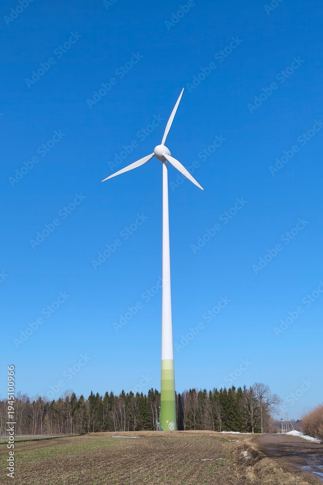 Fototapeta premium Wind power generator isolated against clear blue sky. Modern renewable energy infrastructure and clean electricity production concept.