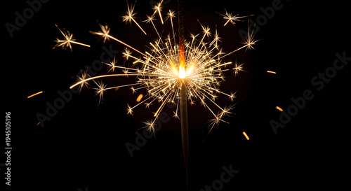 Handheld sparkler firework emitting bright golden sparks against a solid black background