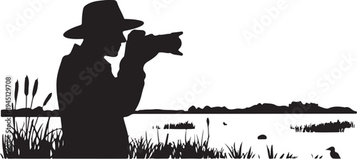 Black silhouette of man in hat photographing lake scene