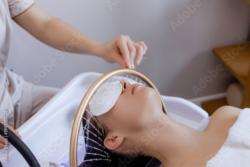 Close-up of a woman receiving a head massage during a Japanese head spa treatment with water flowing from a special hair washing tool, focusing on the scalp relaxation and beauty therapy	