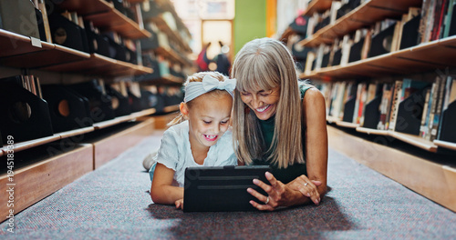 Tableau sur toile Kid, tablet and grandmother in library with learning, reading ebook and literature for development