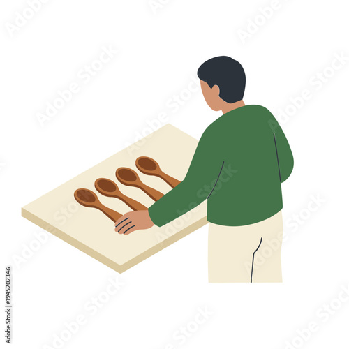 Man arranging wooden spoons on a table in a kitchen environment