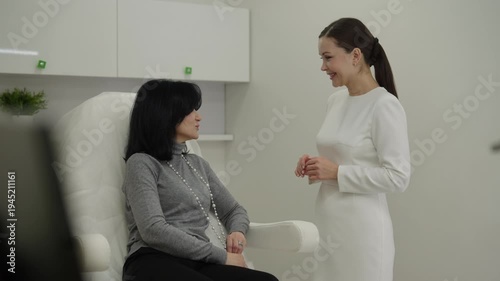 Young female beautician giving professional advice to mature woman client in cosmetology office, explaining cosmetic procedures for skin enhancement and anti aging care. Concept of healthy lifestyle.