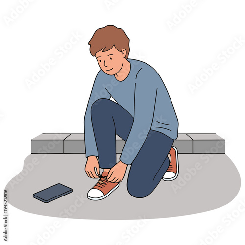 A man kneels on the ground tying his shoelaces beside a phone.