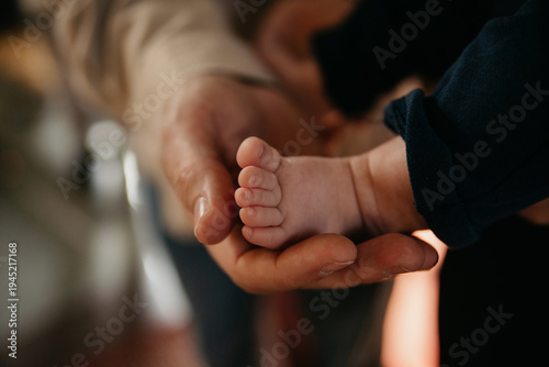 Godfather holds a child's foot in his palm during a baptism ceremony in the church