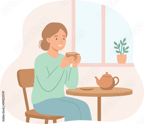 Woman sits at table indoors with teapot and cup smiling
