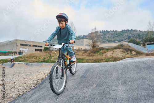 Boy riding bicycle on pump track wearing helmet