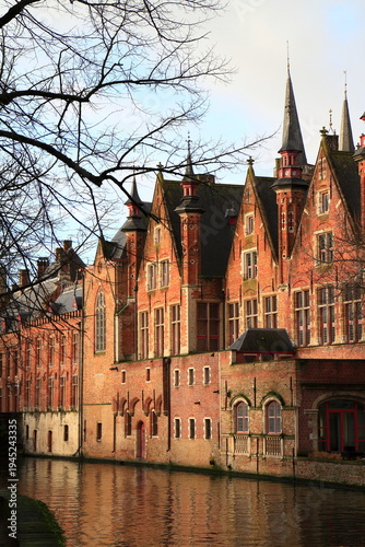 Historic Red Brick Gabled Buildings with Pointed Turrets Line a Reflective Canal in Bruges