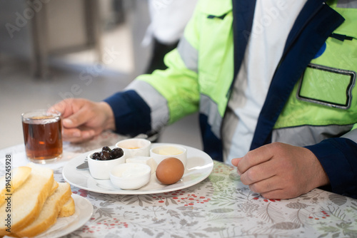 Industrial engineers sitting in canteen and talking on lunch break. Construction company workers in safety uniform eating meal and chatting in modern office