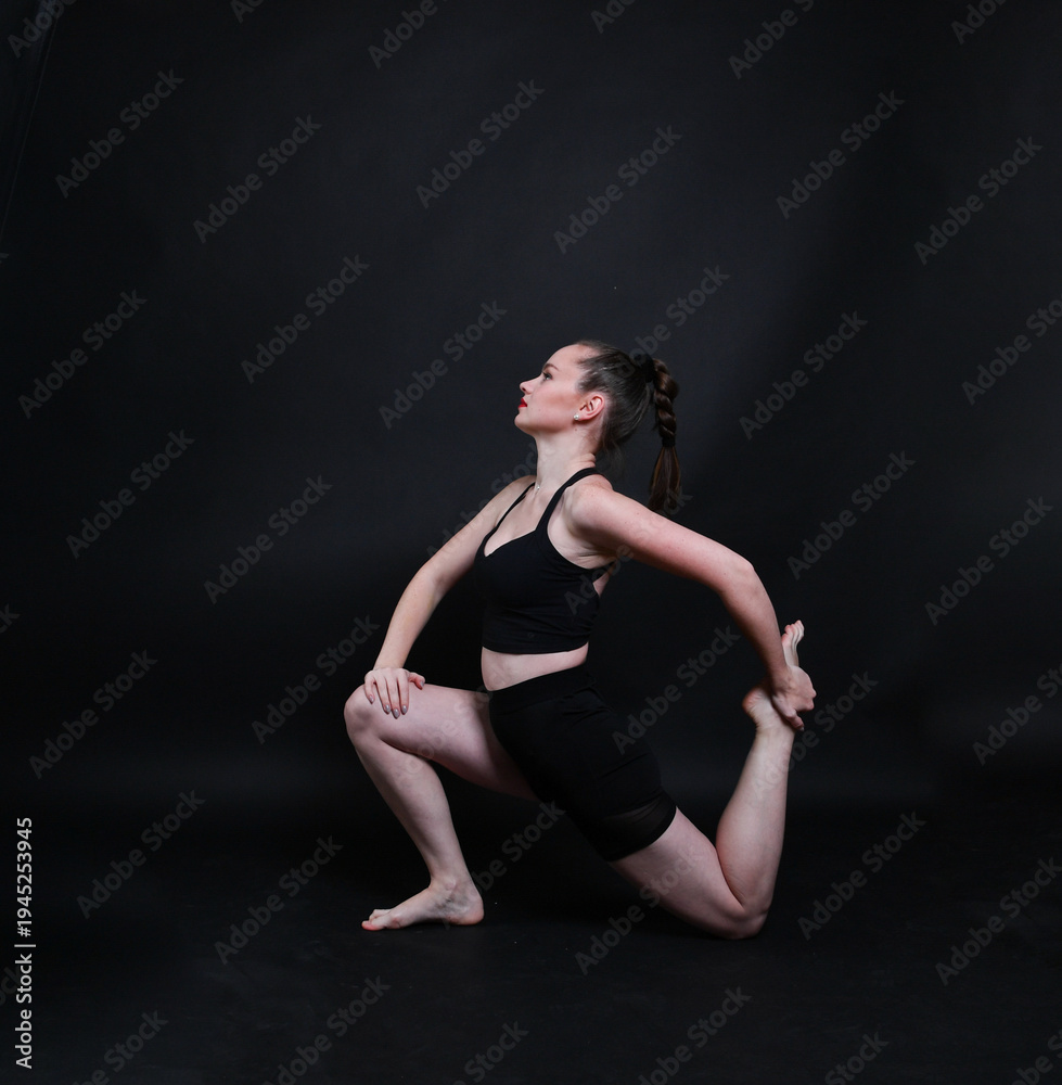 Obraz premium Sportliche Frau macht Dehnübung im Studio. Kombination aus Yoga, Pilates und Fitness-Training zur Entspannung, Beweglichkeit und Körperstärkung. Minimalistische Szene mit ruhigem Hintergrund.