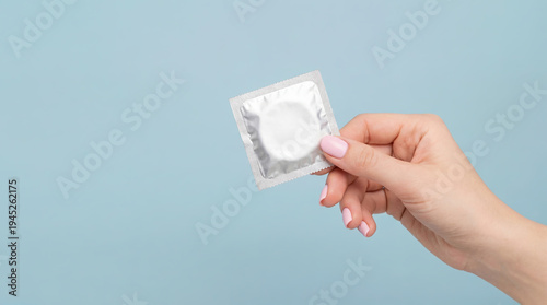 Sexual health care and disease protection: unopened condom in hand on a blue background