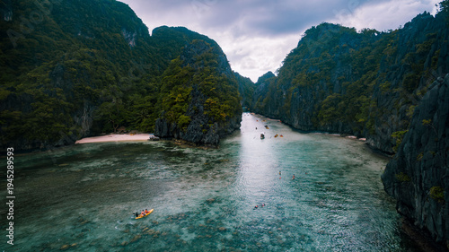 Aerial view of turquoise waters meet the rugged, verdant cliffs in a stunning display of nature's artistry at El Nido, Mimaropa, Philippines.