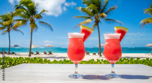 Two pink cocktails with watermelon slices on a beach table outdoor tropical vacation drinks