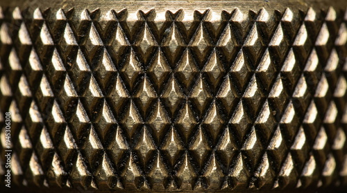 Macro shot of a textured brass surface with a diamond knurling pattern and metallic reflections