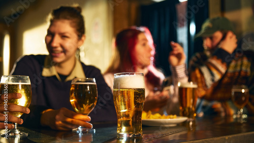 Fotografie Beer glass on bar counter with friends socializing in background during relaxed pub evening for alcohol advertising, brewery promotion and hospitality marketing campaigns