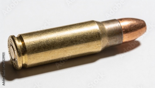 A single brass bullet cartridge with a copper projectile rests on a clean white surface, isolated with a subtle shadow, highlighting its metallic texture and industrial design