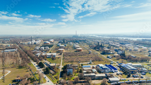 Aerial view of industrial zone with silver tanks and smokestacks puncturing the skyline under a bright blue sky, Novi Sad, Vojvodina, Serbia.