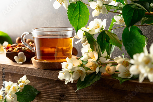 Glass cup of jasmine tea and green jasmine branches with flowers.