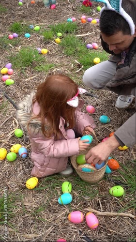 Father and daughter collecting colorful plastic easter eggs