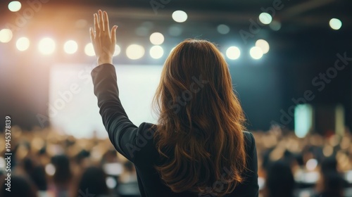 A confident businesswoman waving her hand in a crowded auditorium during a presentation