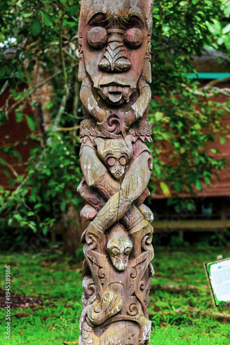Detailed Carved Wood Totem Pole Sculpture in a Lush Garden Setting