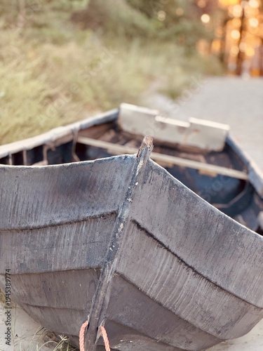 Old wooden fishing boat resting on sandy beach at sunset. Weathered wooden fishing boat resting on a sandy beach with warm sunset light in the background. 