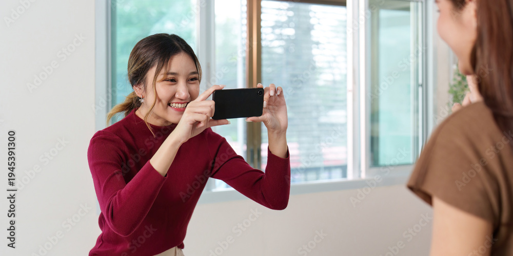 Fototapeta premium Capturing Smiles. Woman taking photo of her friend with smartphone.