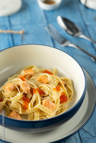 Fettuccine pasta with salmon and red caviar on blue wood
