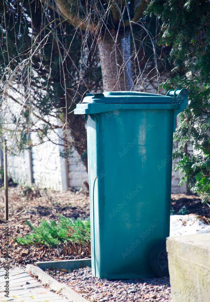 Obraz premium Green garbage bin standing outdoors in residential yard