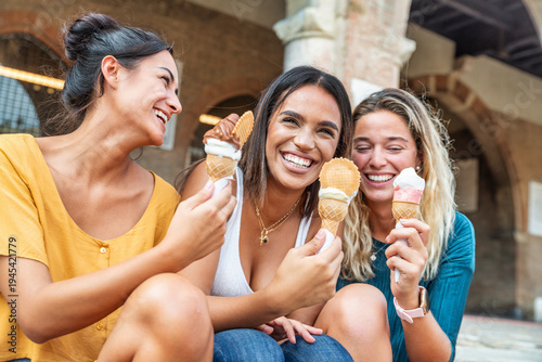 Happy female friends eating ice cream outside - Smiling young women having fun in city street