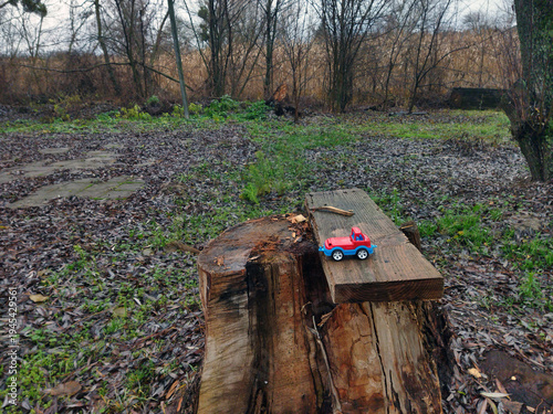 Small red toy truck on a wooden stump in a wooded area