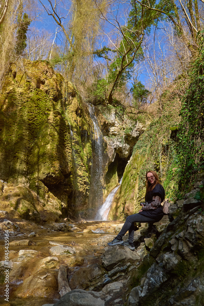 Obraz premium girl on the background of a large beautiful waterfall in the gorge