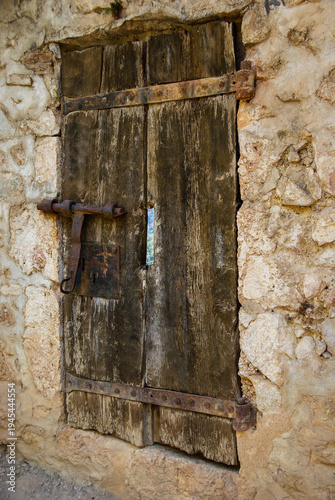 Old wooden door securing stone wall building entrance