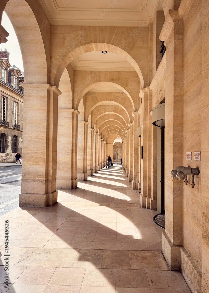 Obraz premium Walking under a sunlit arcade in Paris, France. 