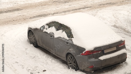 Ośnieżony samochód stojący na parkingu pod blokiem