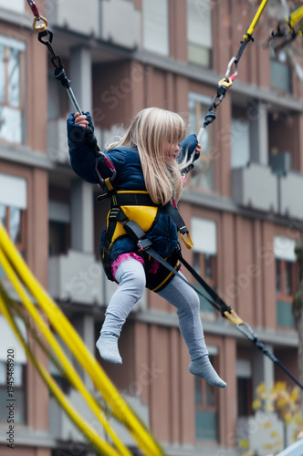 little blonde girl jumping on a bungee