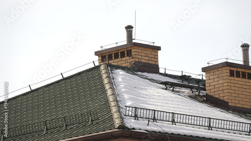 Dach domu wielorodzinnego ośnieżony z jedne strony.