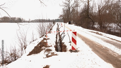 Roboty drogowe wzdłuż wiejskiej nieutwardzonej drogi. Kładzenie kabli przy drodze.