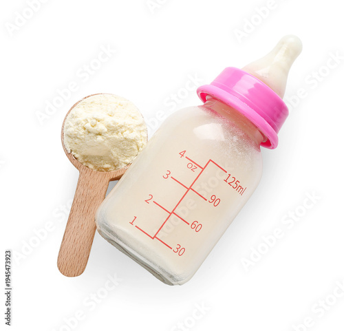 Measuring scoop with powdered baby milk formula and bottle on white background