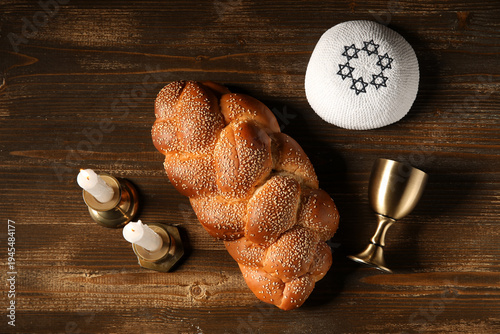 Φωτογραφία Traditional challah bread with wine goblet, kipa and burning candles on wooden table