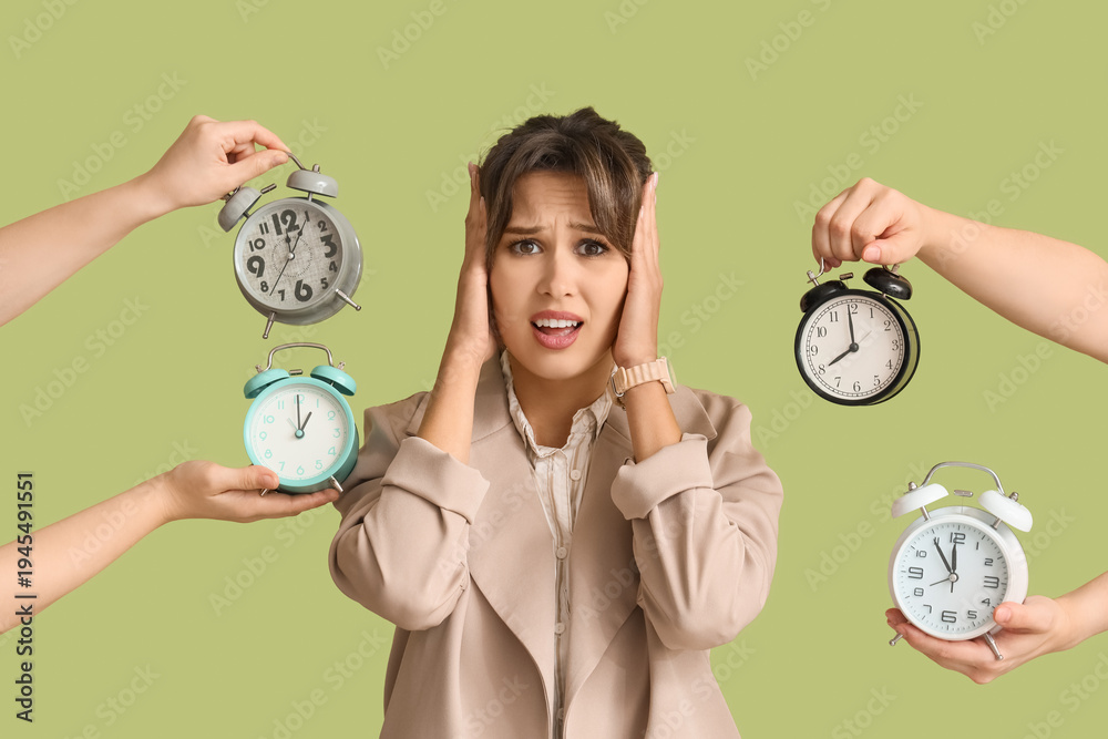 Naklejka premium Shocked young businesswoman surrounded by hands with alarm clocks on green background. Deadline concept