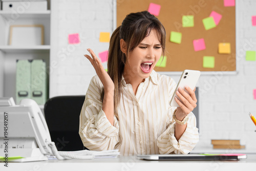 Quadro em tela Screaming young businesswoman with mobile phone at her workspace in office