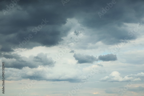 Dramatic dark storm clouds over pale blue sky with layered overcast atmosphere and moody weather background