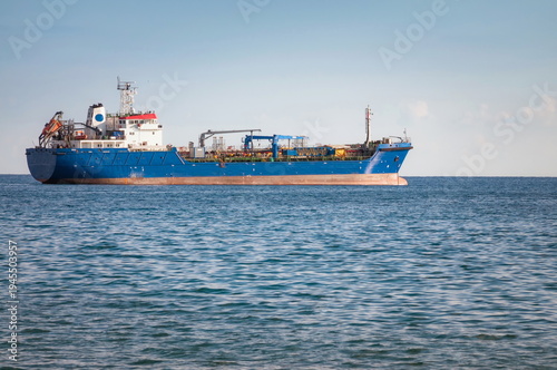 Stock images of Ship carrying containers with crude oil barrels from the harbour. Ship blocked in harbour.
